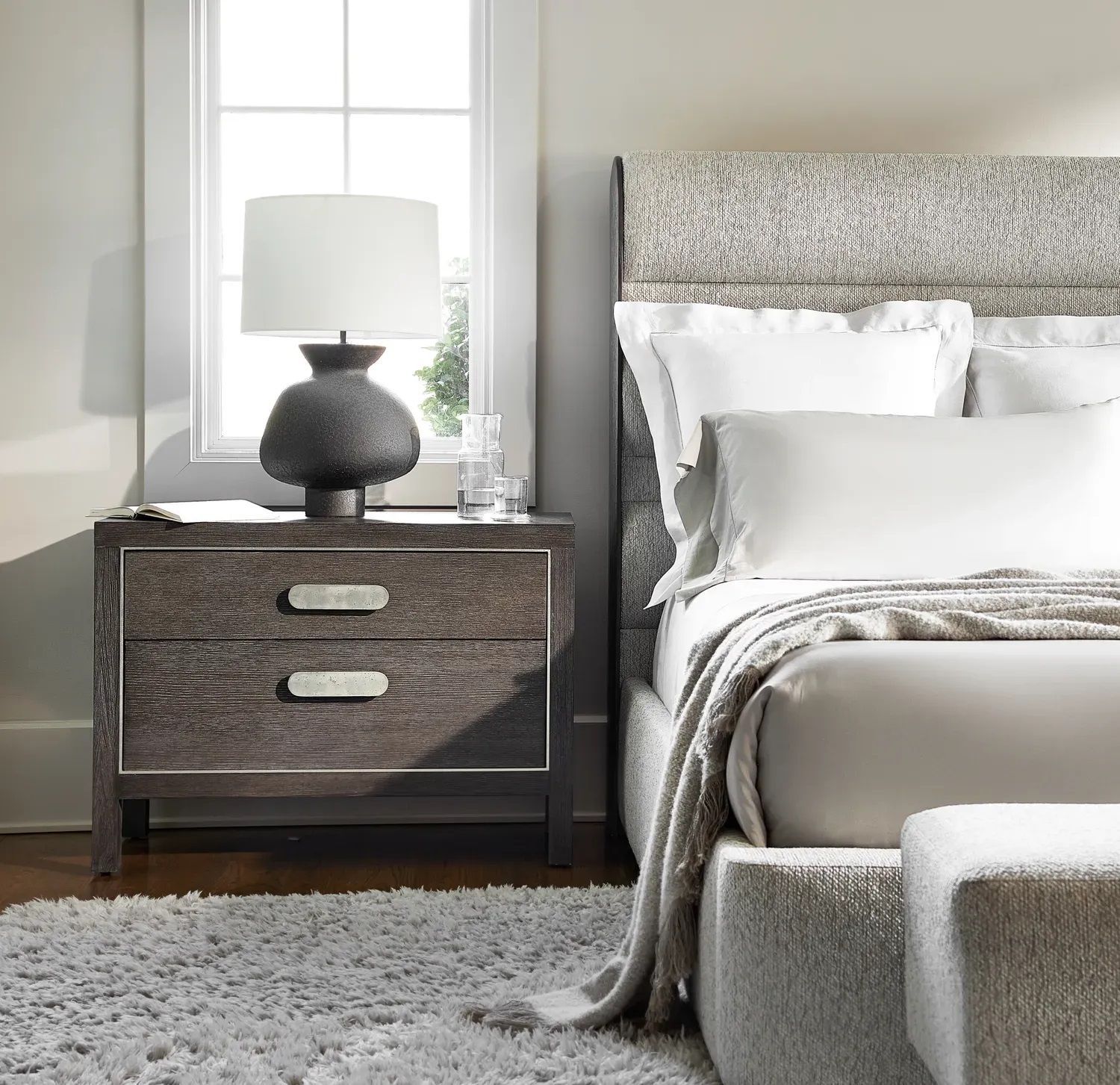 A bedroom with a bed a nightstand and a lamp