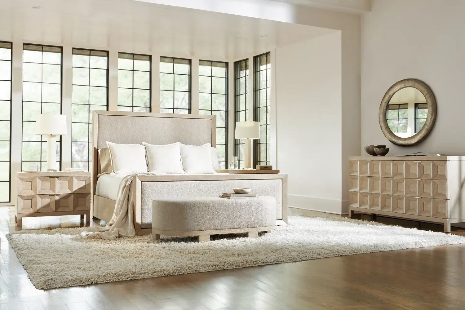 A bedroom with a bed, dresser, nightstand, mirror, and rug.