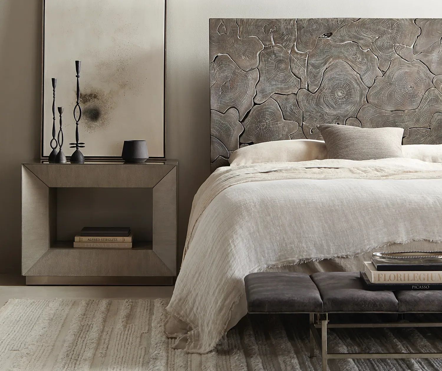 A bedroom with a bed, nightstand, and bench