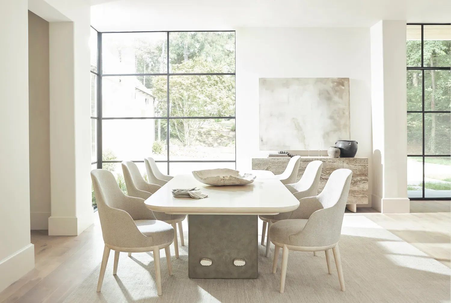 A dining room with a long table and chairs in front of a large window.