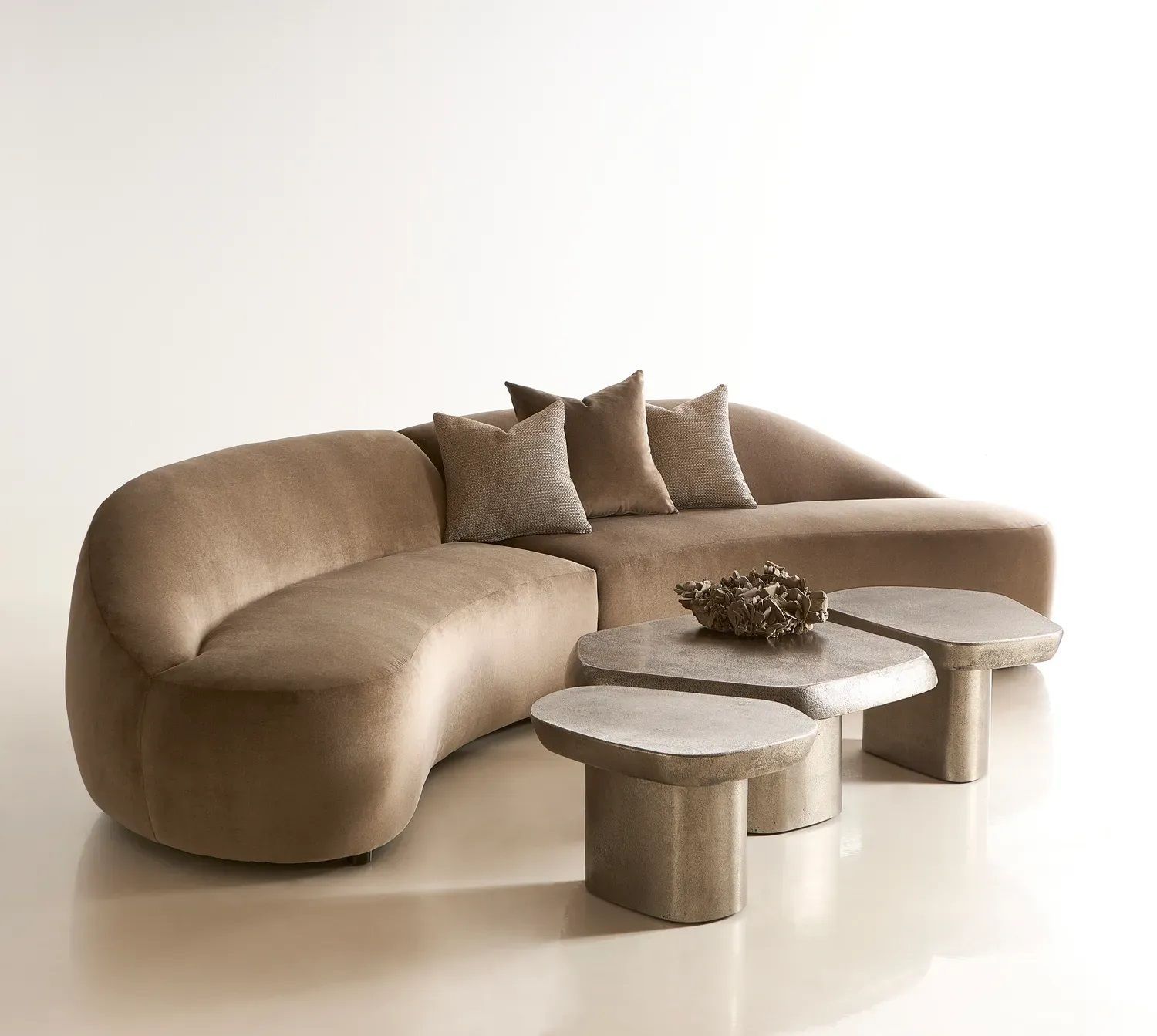 A curved couch with two coffee tables next to it