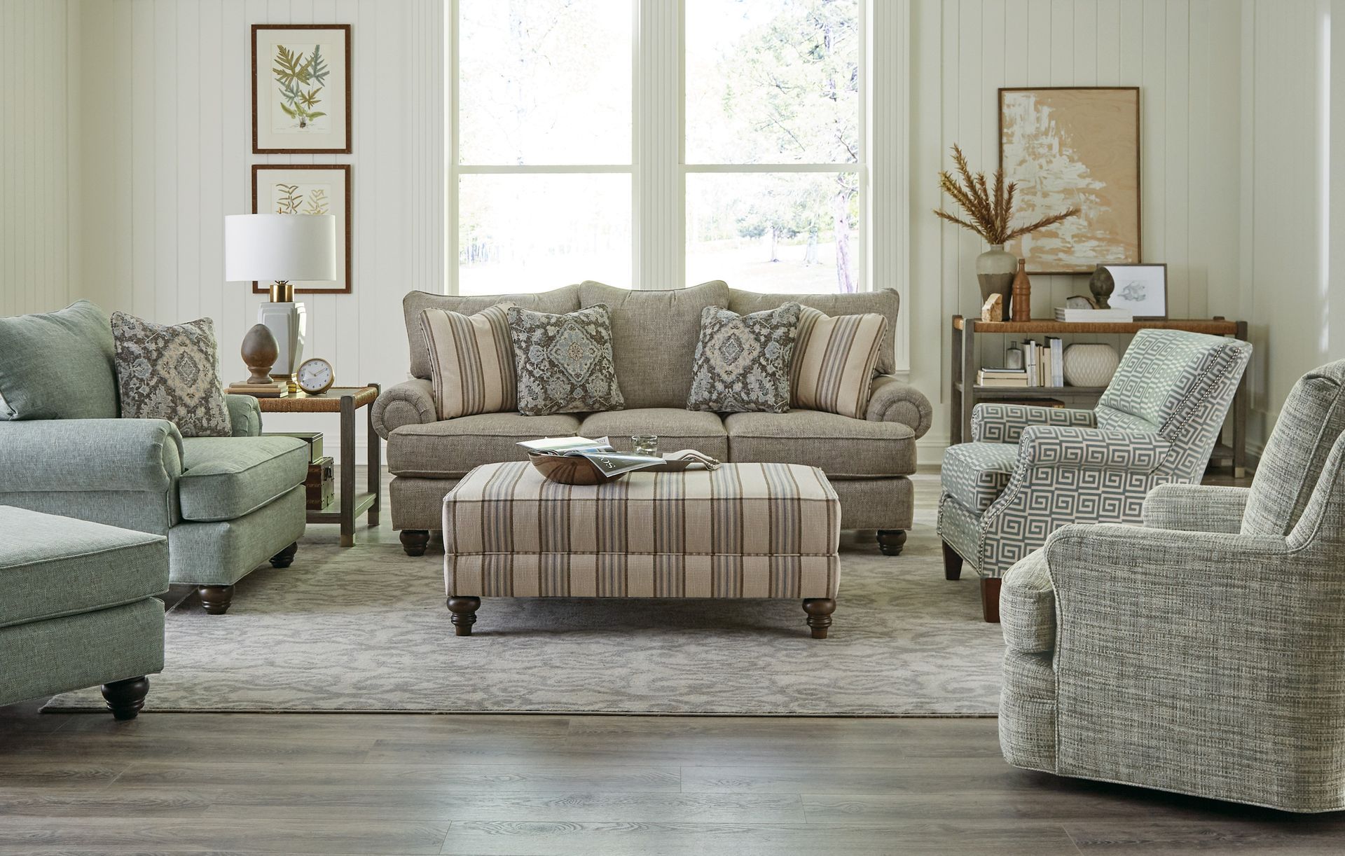 A living room with a couch , chairs , and ottoman.