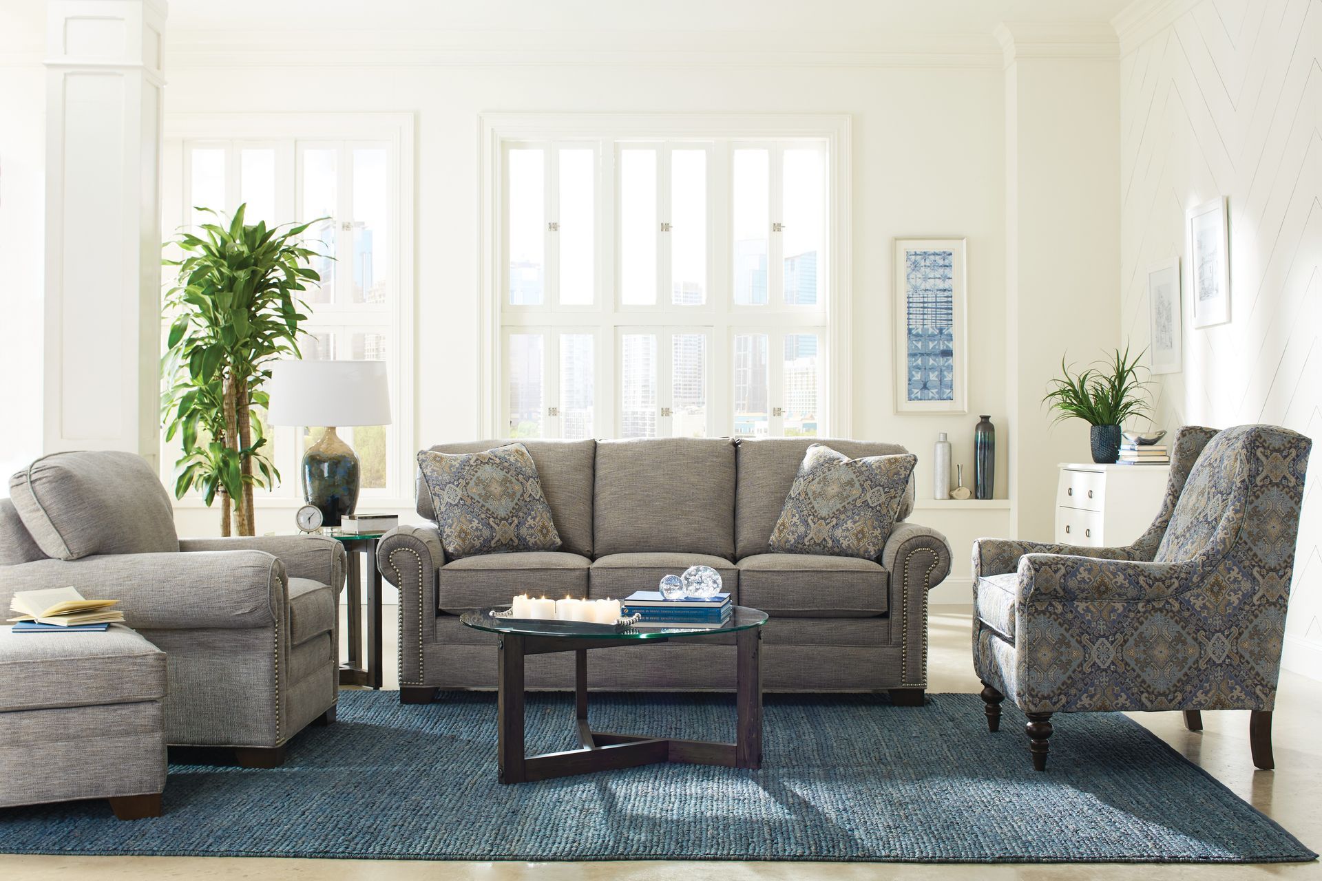 A living room with a couch , chair , ottoman and coffee table.