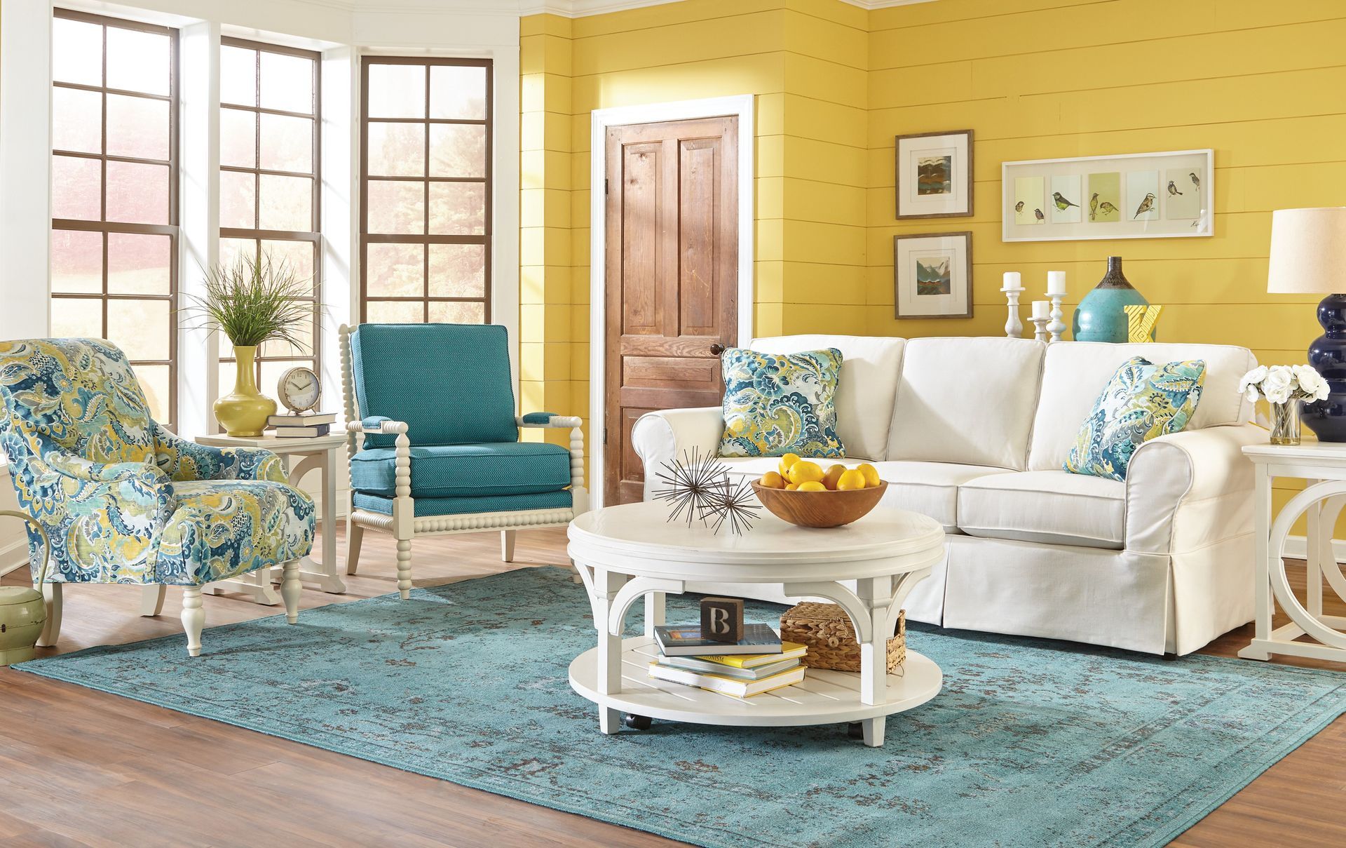 A living room with a white couch , blue chairs , and a blue rug.