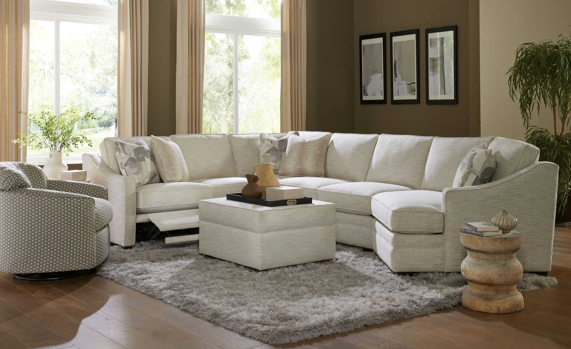 A living room with a sectional couch , chair , ottoman and rug.