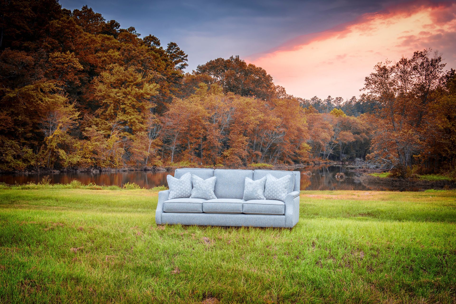 A couch is sitting in the middle of a grassy field.