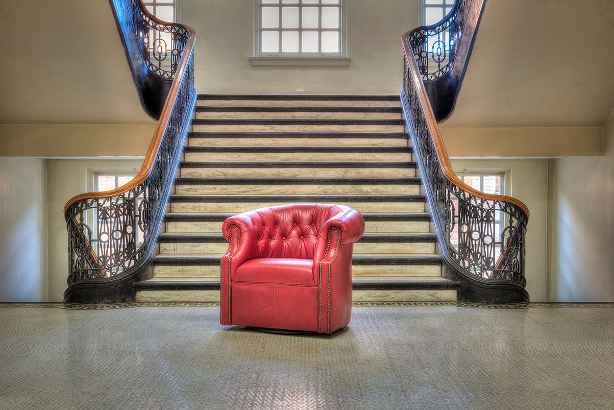 A red chair is sitting in front of a set of stairs.