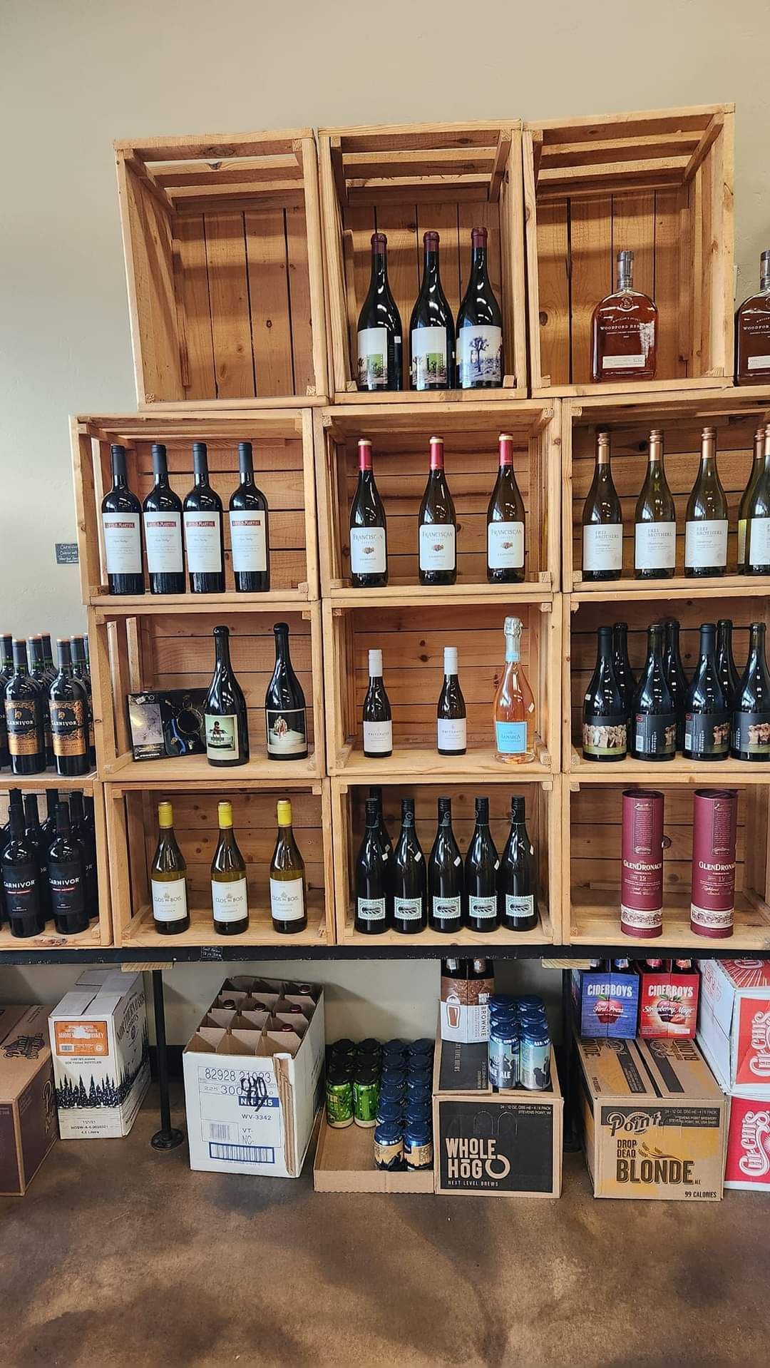 Wooden crate shelves stocked with assorted bottled beers and drinks in a shop display.