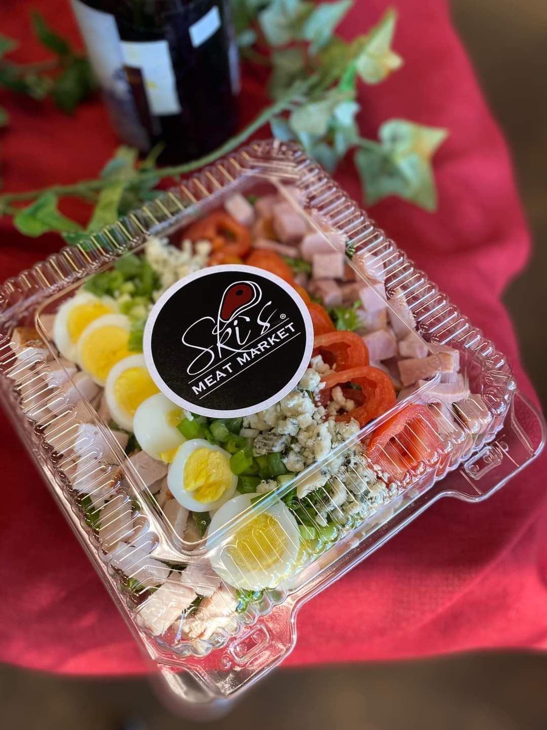 Assorted sushi platter in a clear plastic container on a red tablecloth
