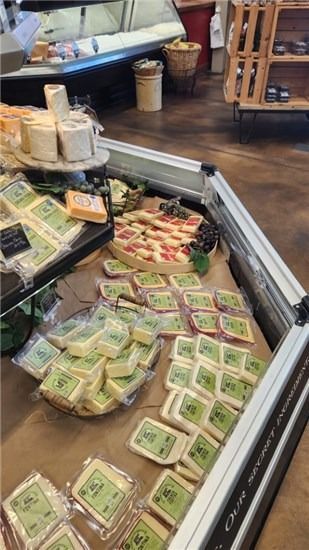 Assorted packaged cheeses and deli items in a grocery store refrigerated display case