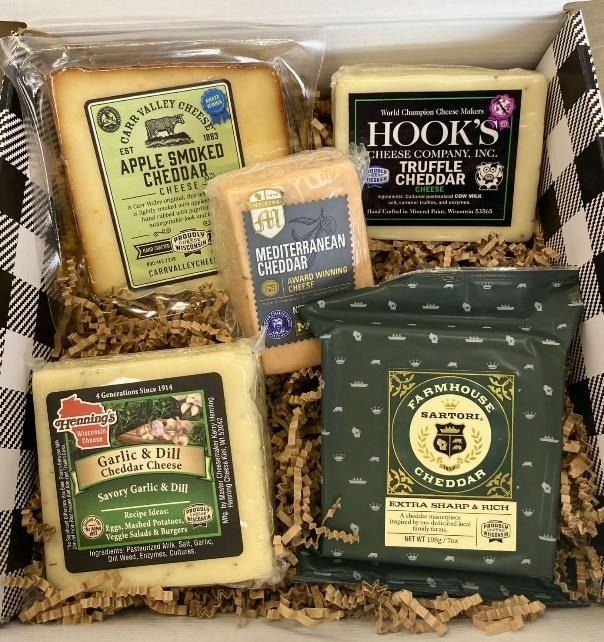 Gift box of assorted artisan cheddar cheese wedges in green, black, and tan packaging with straw filler
