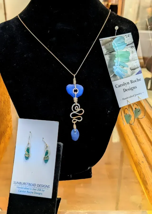Necklace with blue pendant displayed on black jewelry bust in a shop window.