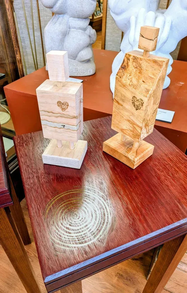 Two small carved stone figurines on a glossy reddish wooden table.