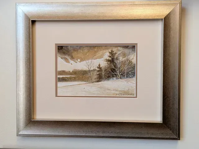 Framed winter landscape painting with trees, snowy hills, and a muted beige mat.
