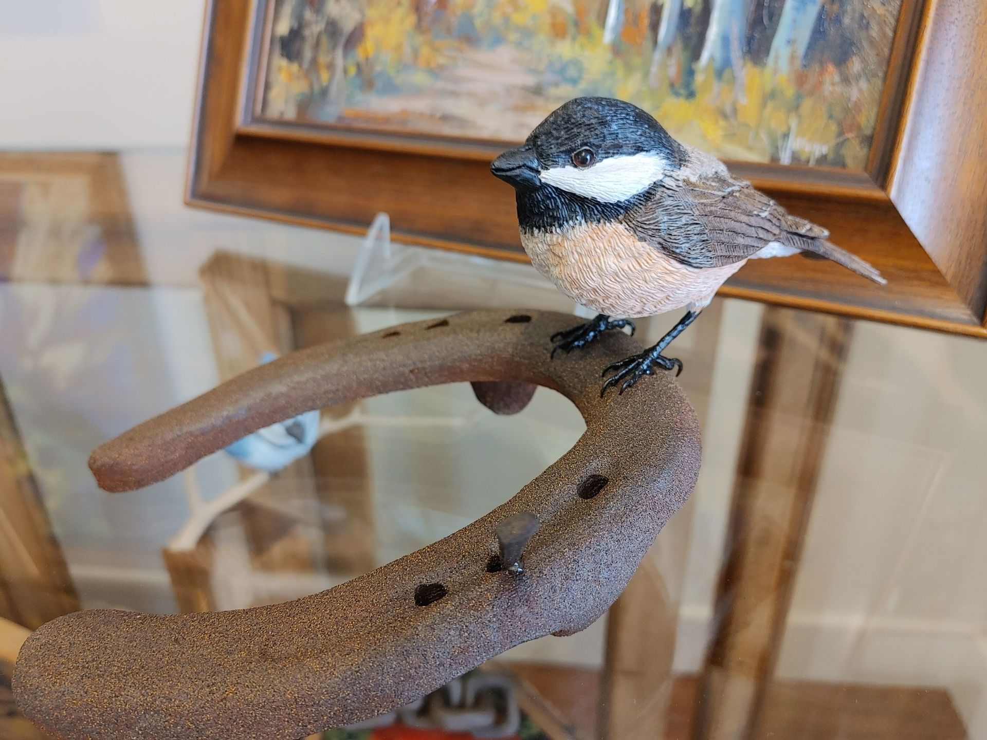 Small bird perched on a curved branch inside a glass display case.