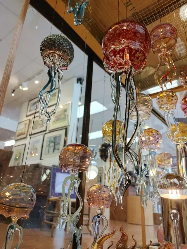 Colorful hanging glass jellyfish sculptures with long tentacles in a shop display.