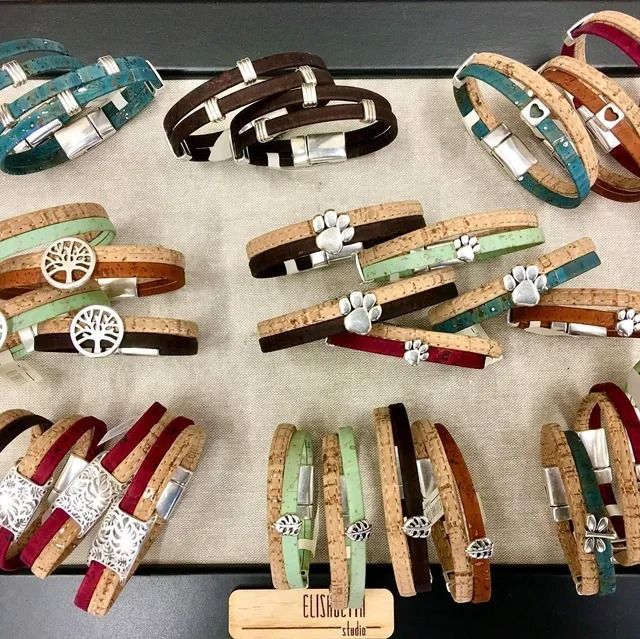 Assorted colorful leather wrap bracelets with charms arranged on a display board.