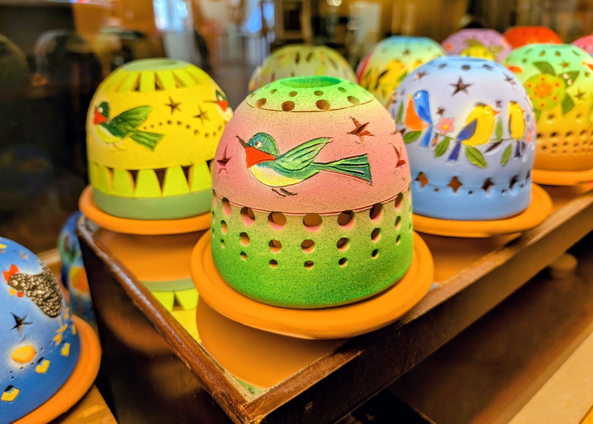 Colorful decorated round cakes on orange trays in a bakery display.