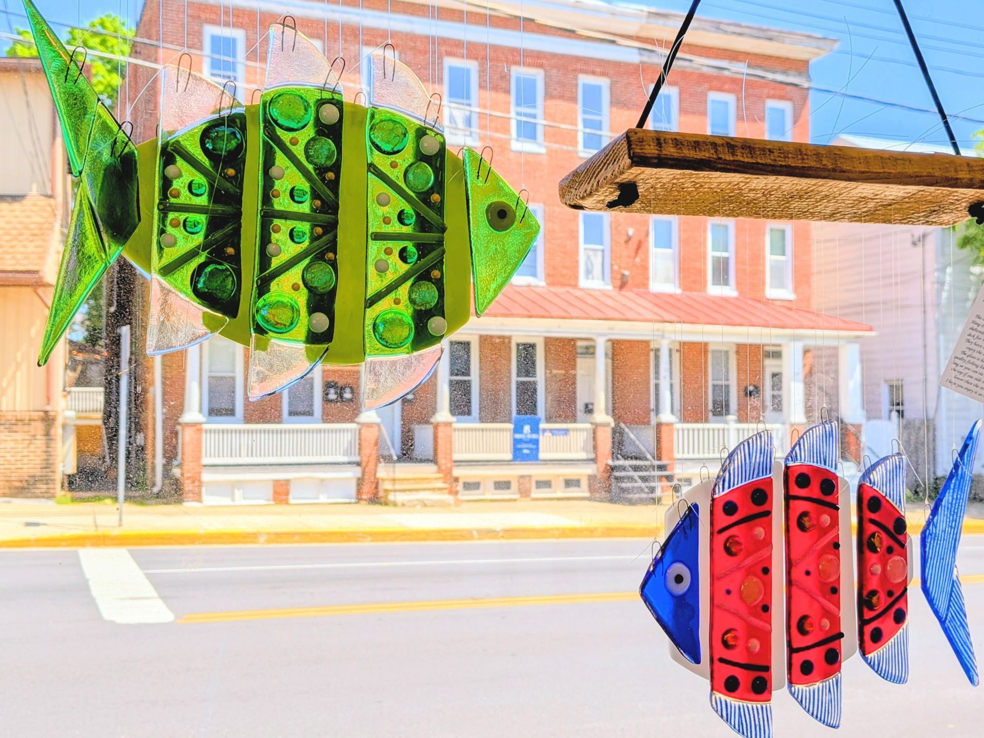Colorful fish-shaped kites suspended in front of a brick building on a city street.