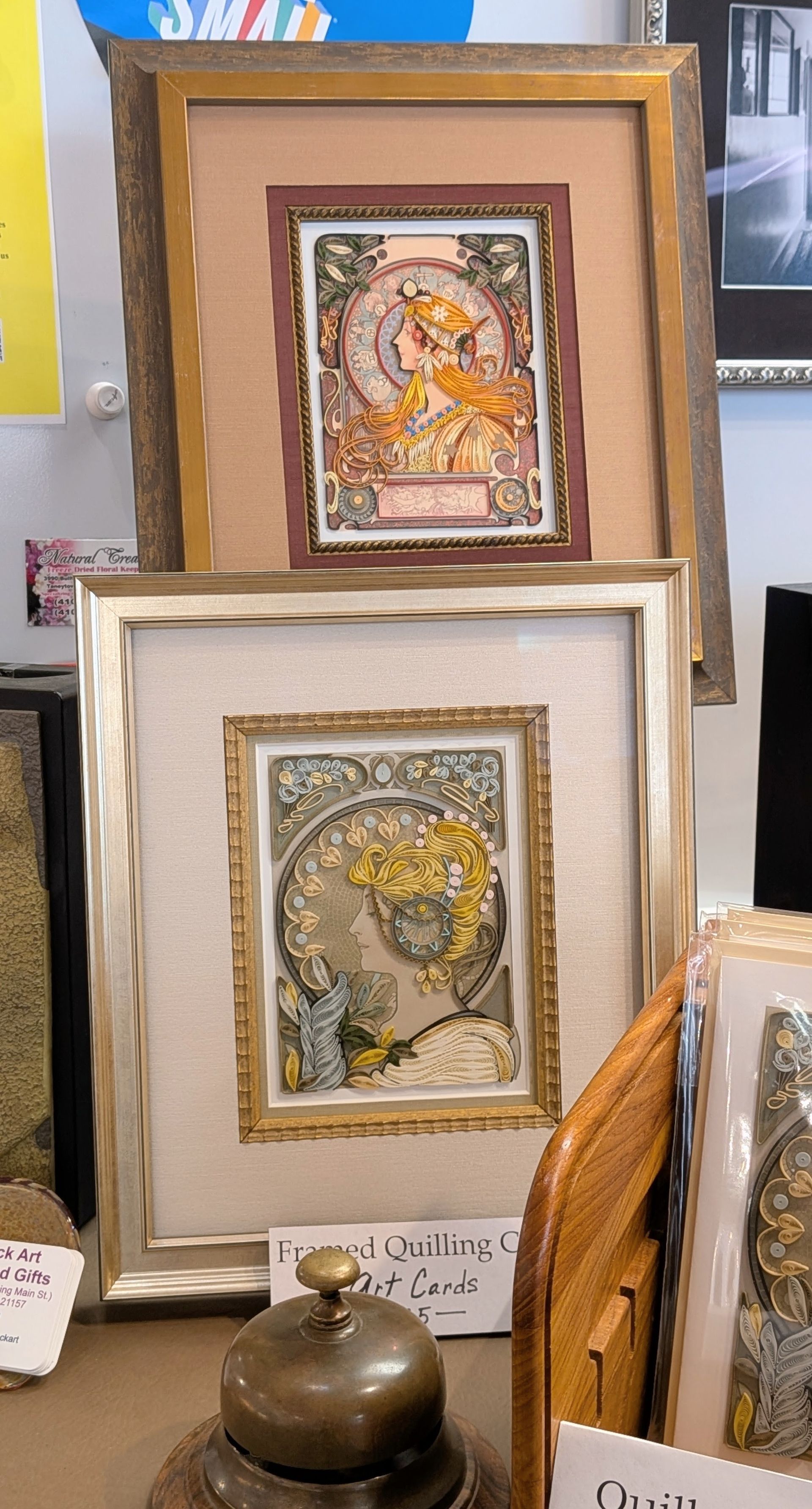 Framed colorful art prints displayed vertically on a table at an art market.
