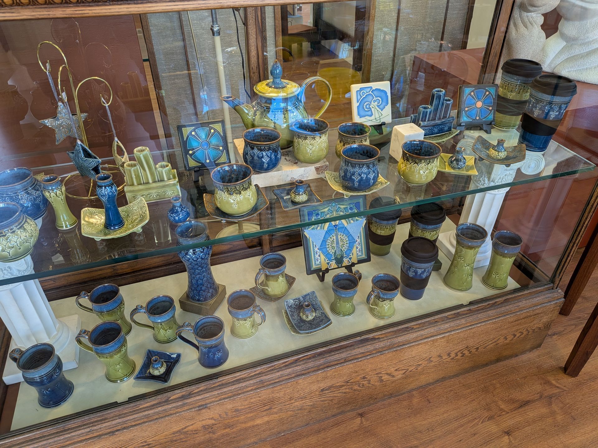 Glass display case with small blue and gold decorative bottles and bowls on wooden shelves.