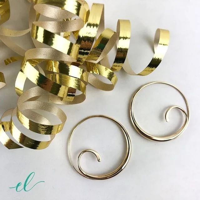 Gold metallic spiral confetti with two small coiled gold rings on a white background.
