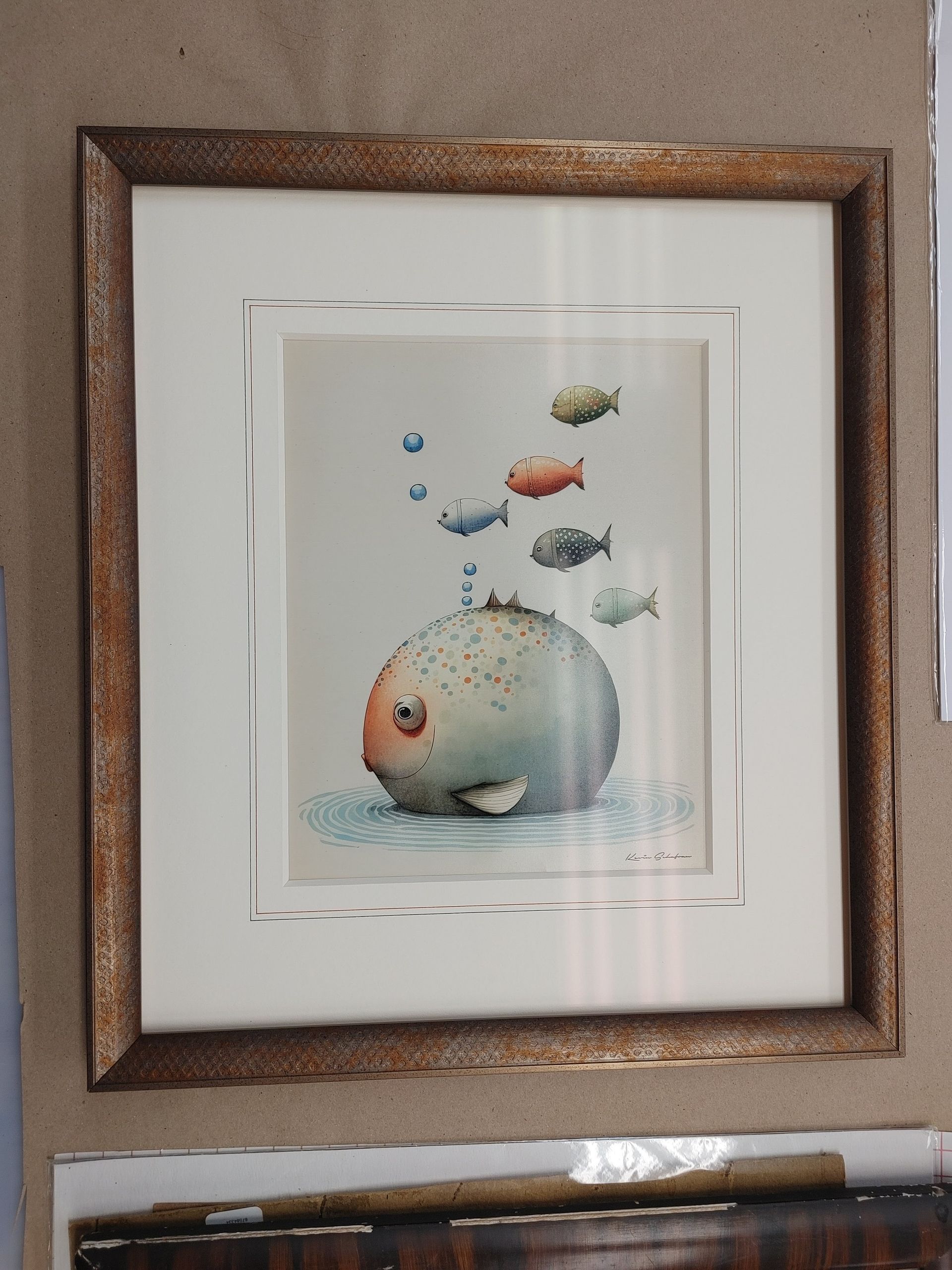 Framed watercolor of a round fish with small colorful fish swimming above it.