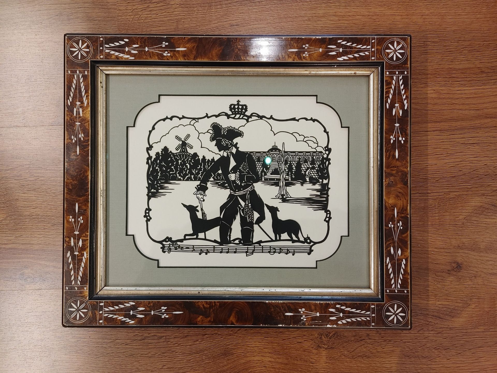 Framed black-and-white winter scene on a wooden wall, showing people with a horse-drawn sleigh.