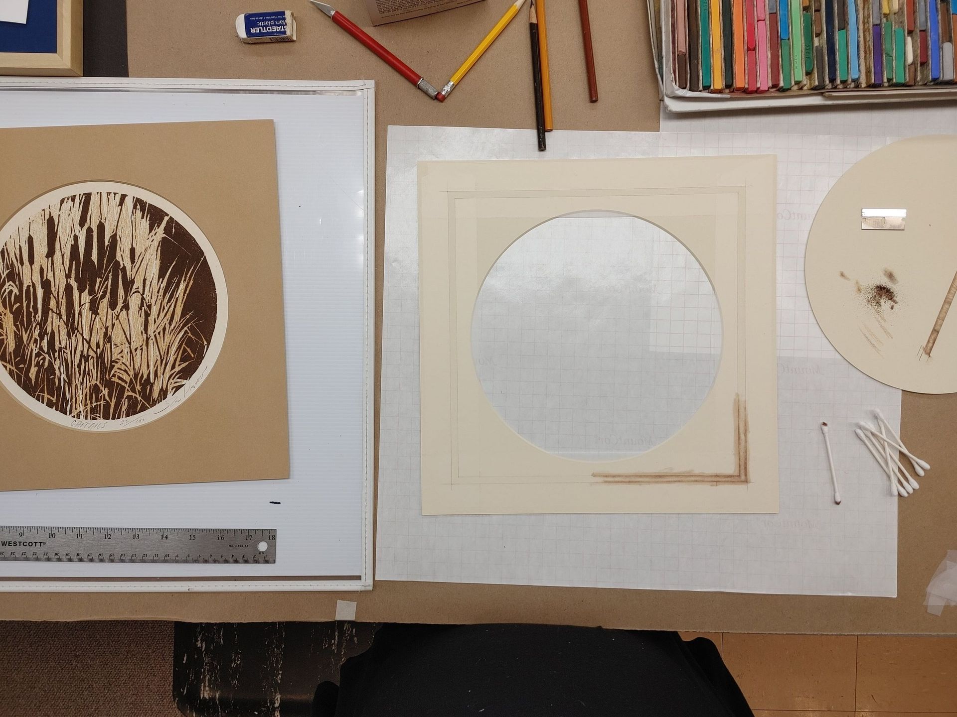 Three paper circles in tan and white on a corkboard work surface with pencils above.