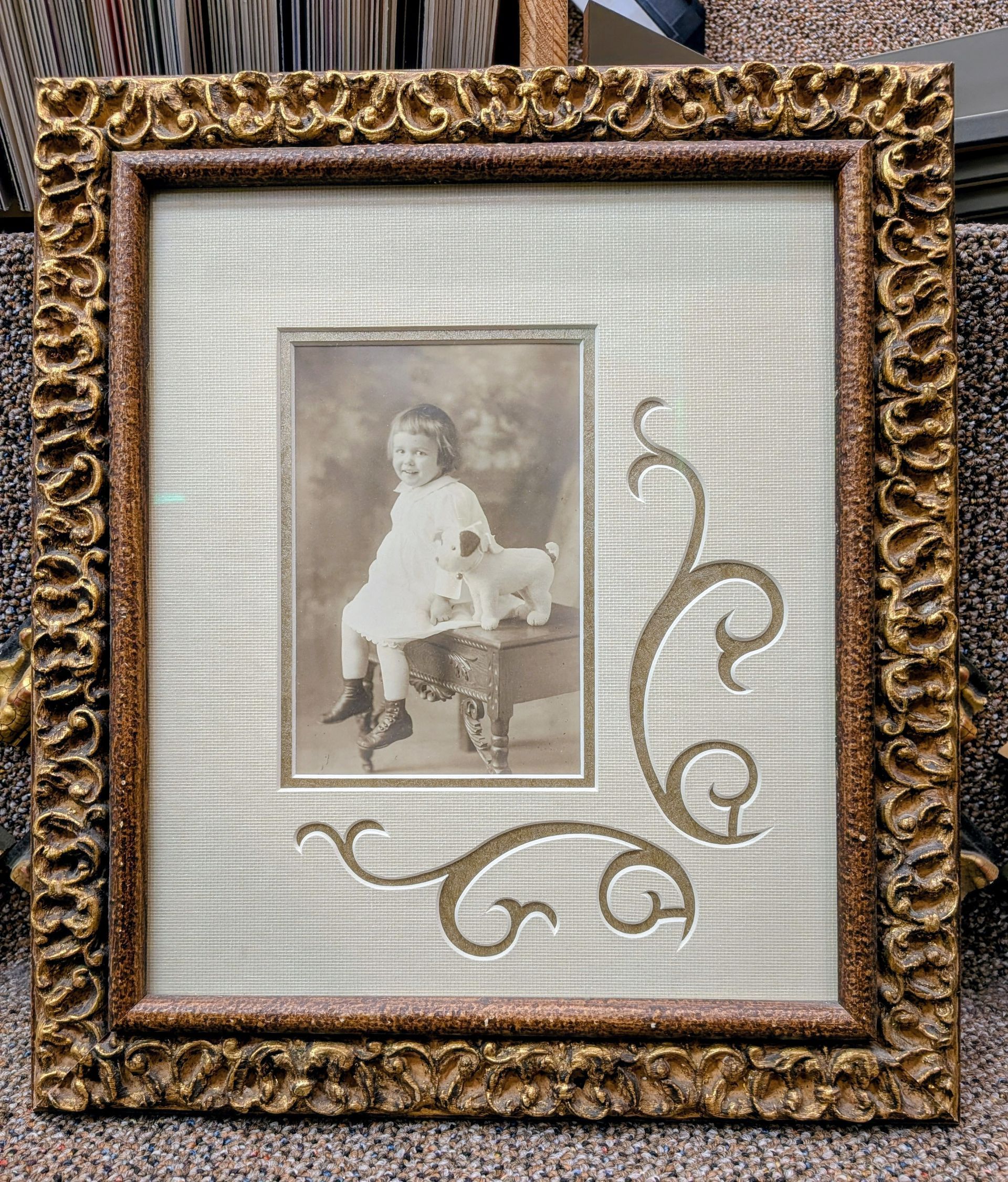 Ornate gold-framed vintage portrait with a sepia child photo and decorative swirls.