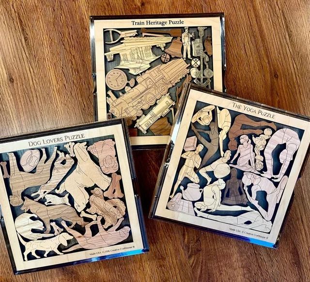 Three carved wooden framed relief art pieces displayed on a wooden floor, showing monochrome scenes.