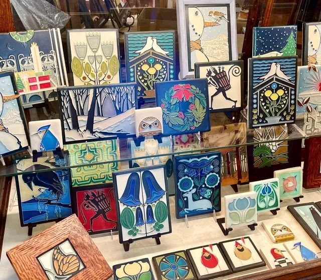 Colorful ceramic tile display with birds, leaves, and abstract patterns arranged on a market rack
