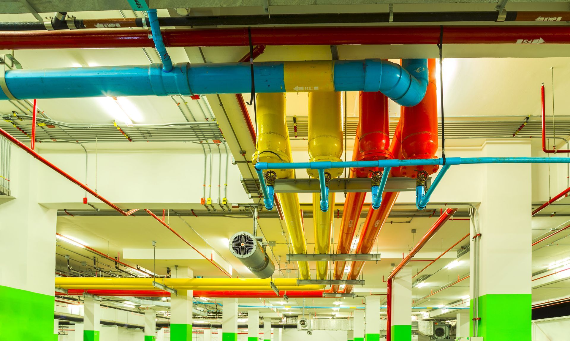 Colorful pipes on a ceiling, likely for utilities, in a commercial building.