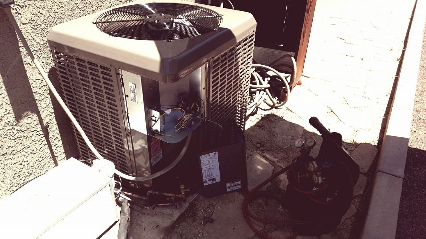 Air conditioner unit with open panels, on a concrete surface, near a building.