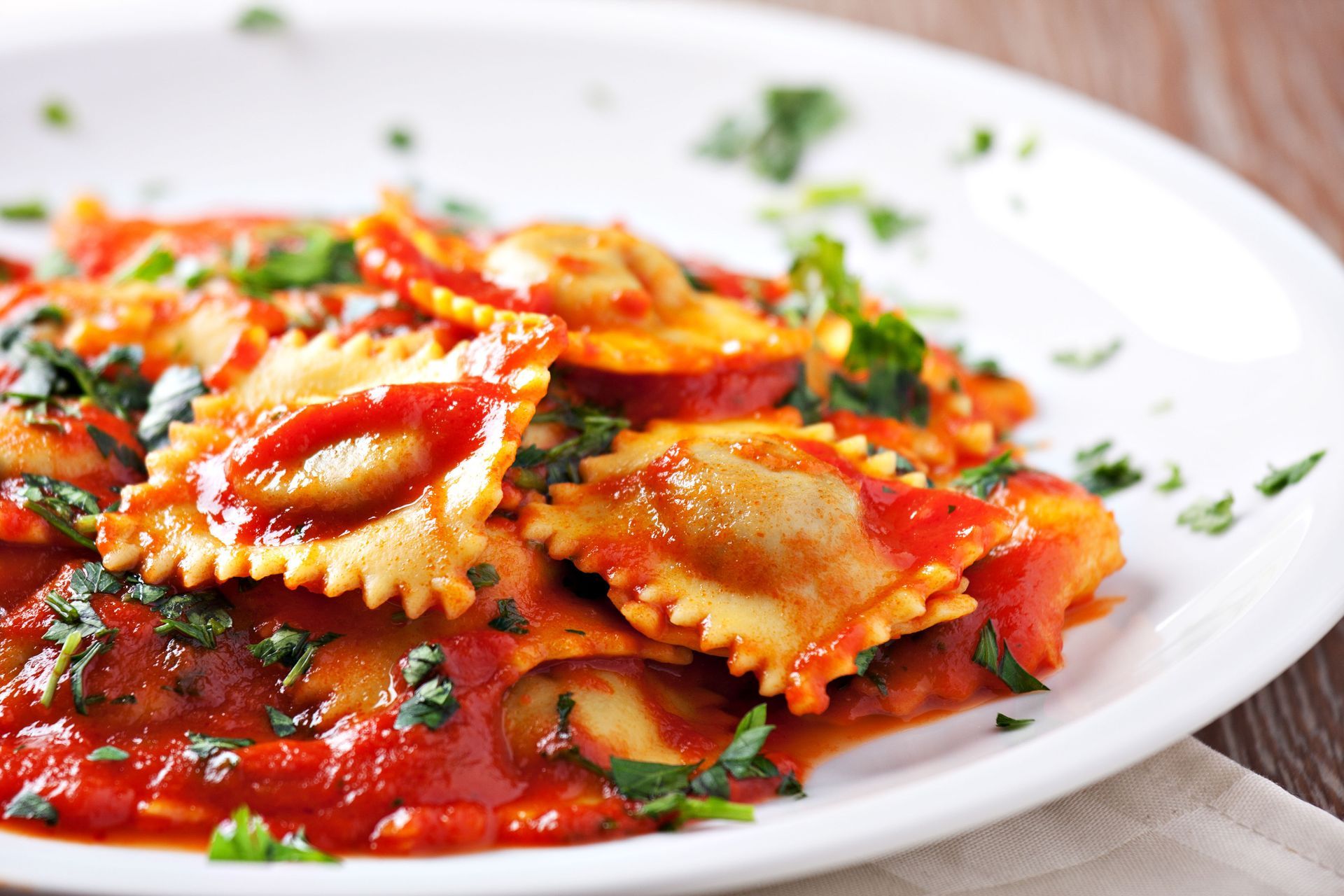 A white plate topped with ravioli and tomato sauce.
