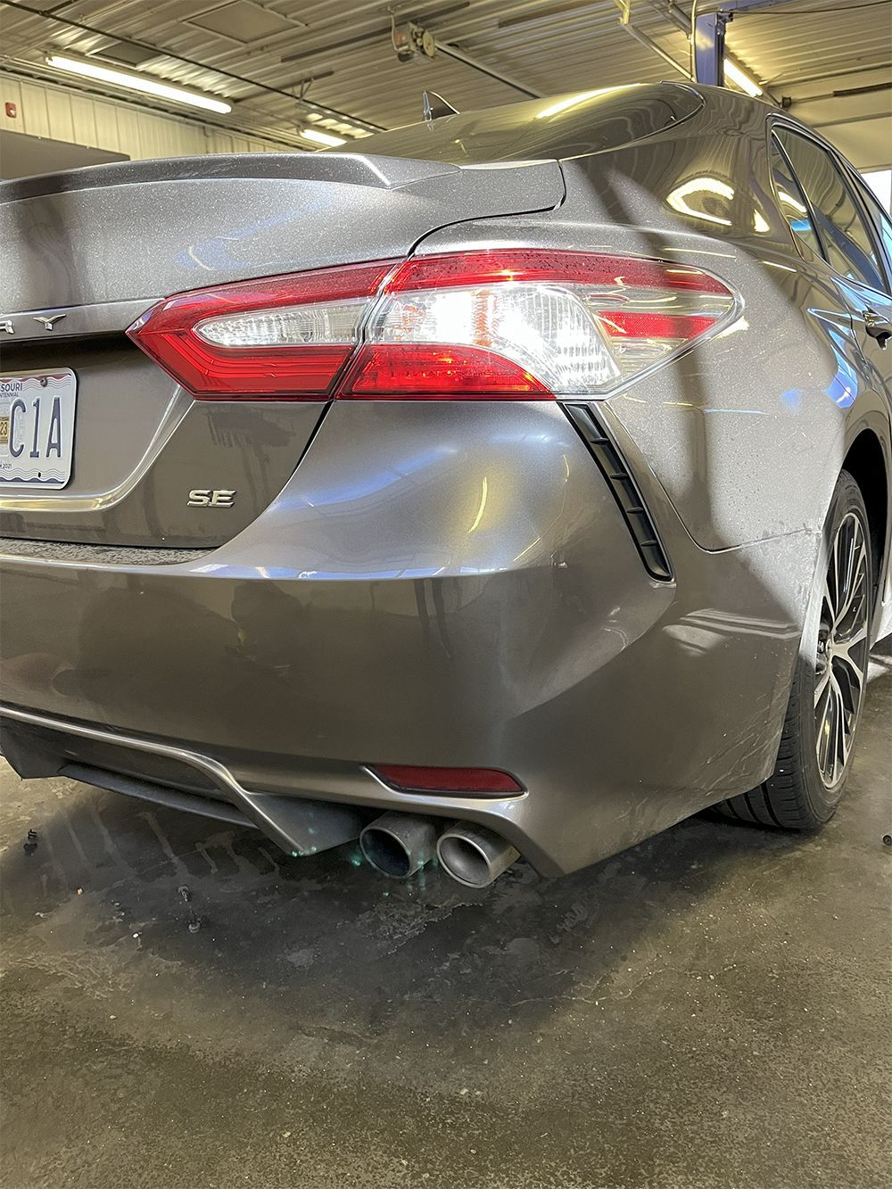 Gray Toyota Camry with damage to the rear bumper, in an auto repair shop - after.