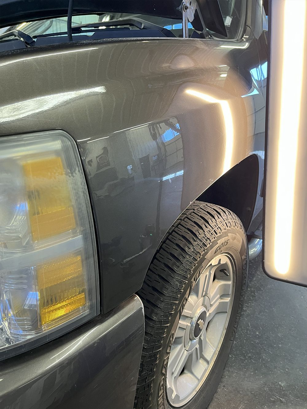 Silver truck with dent in front fender being repaired - after.
