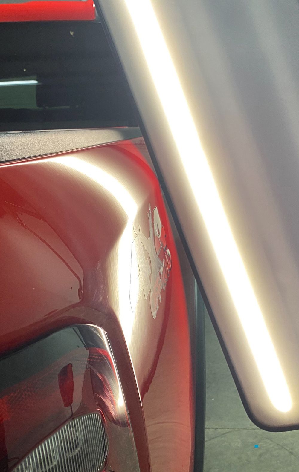 Red car panel with dent being inspected under a light - after.
