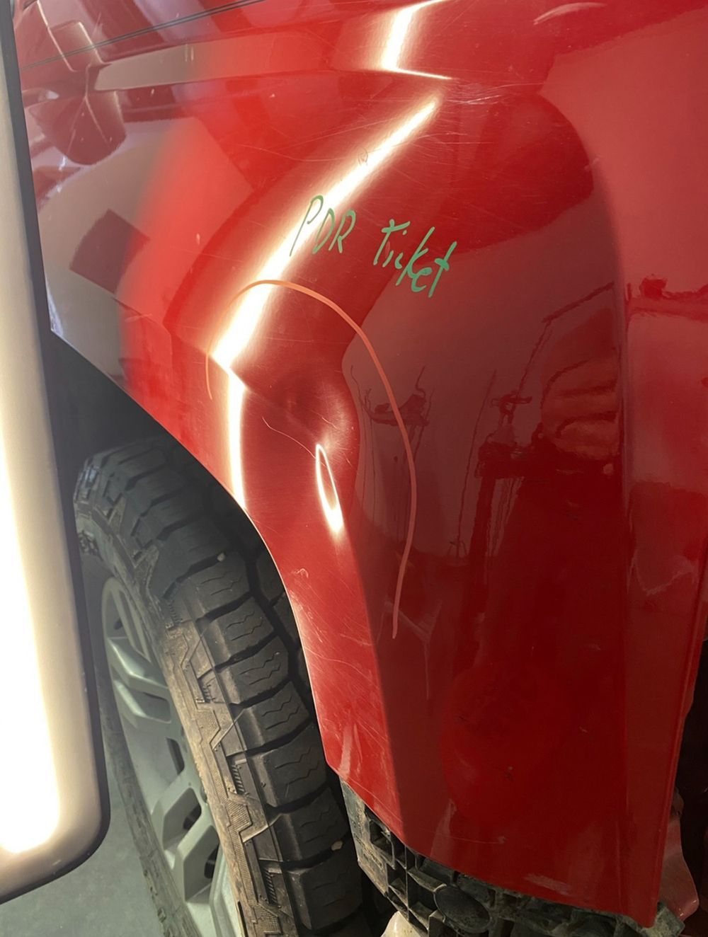 Red car fender with a dent and scratches marked 