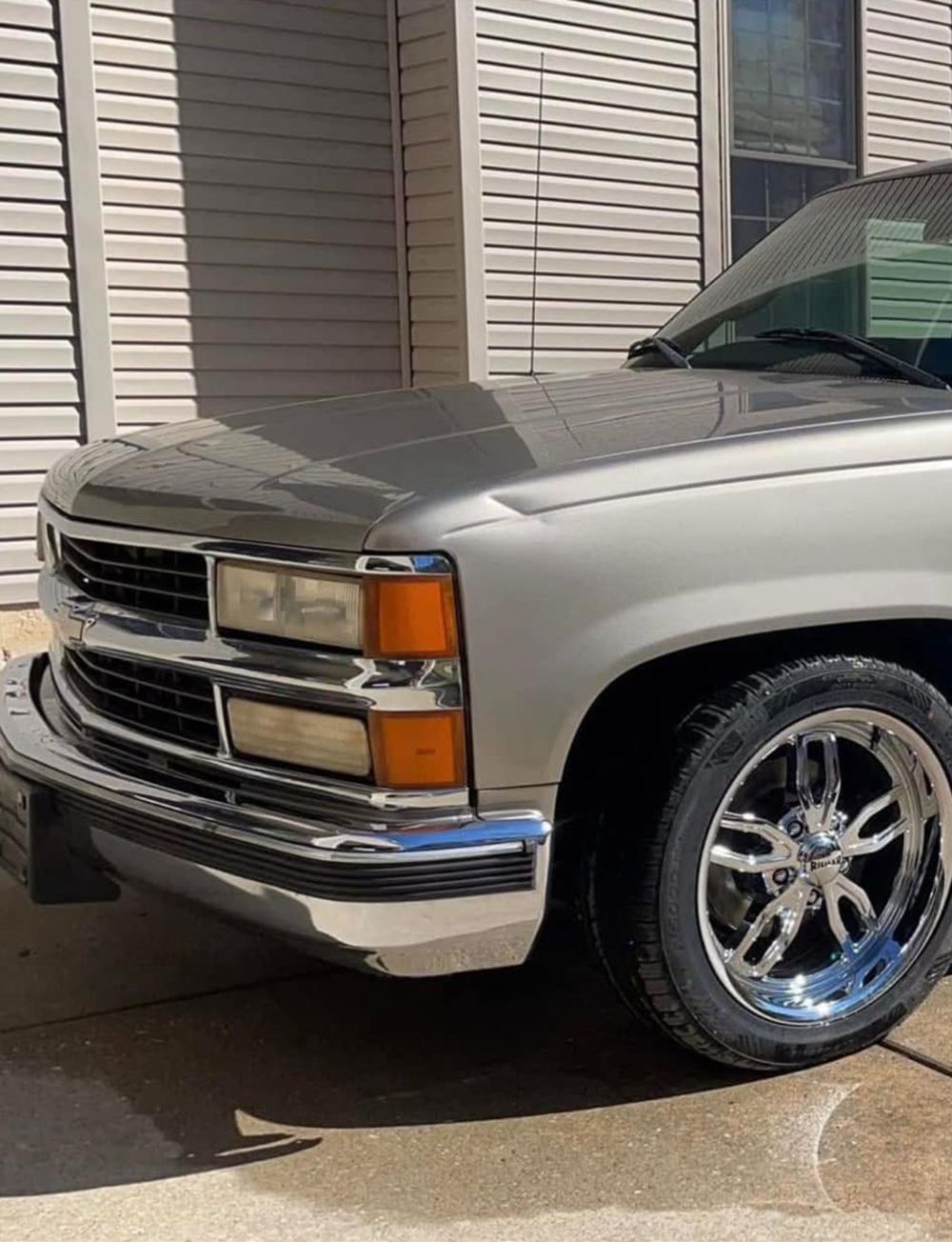 Silver Chevrolet truck with chrome wheels and trim parked outside - before.