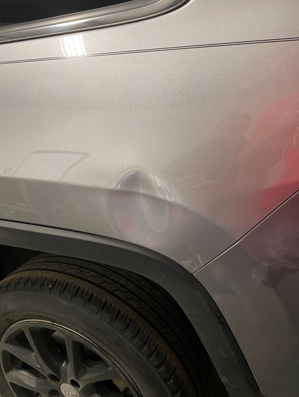 Gray car rear quarter panel with dent near gas door and black tire - before.