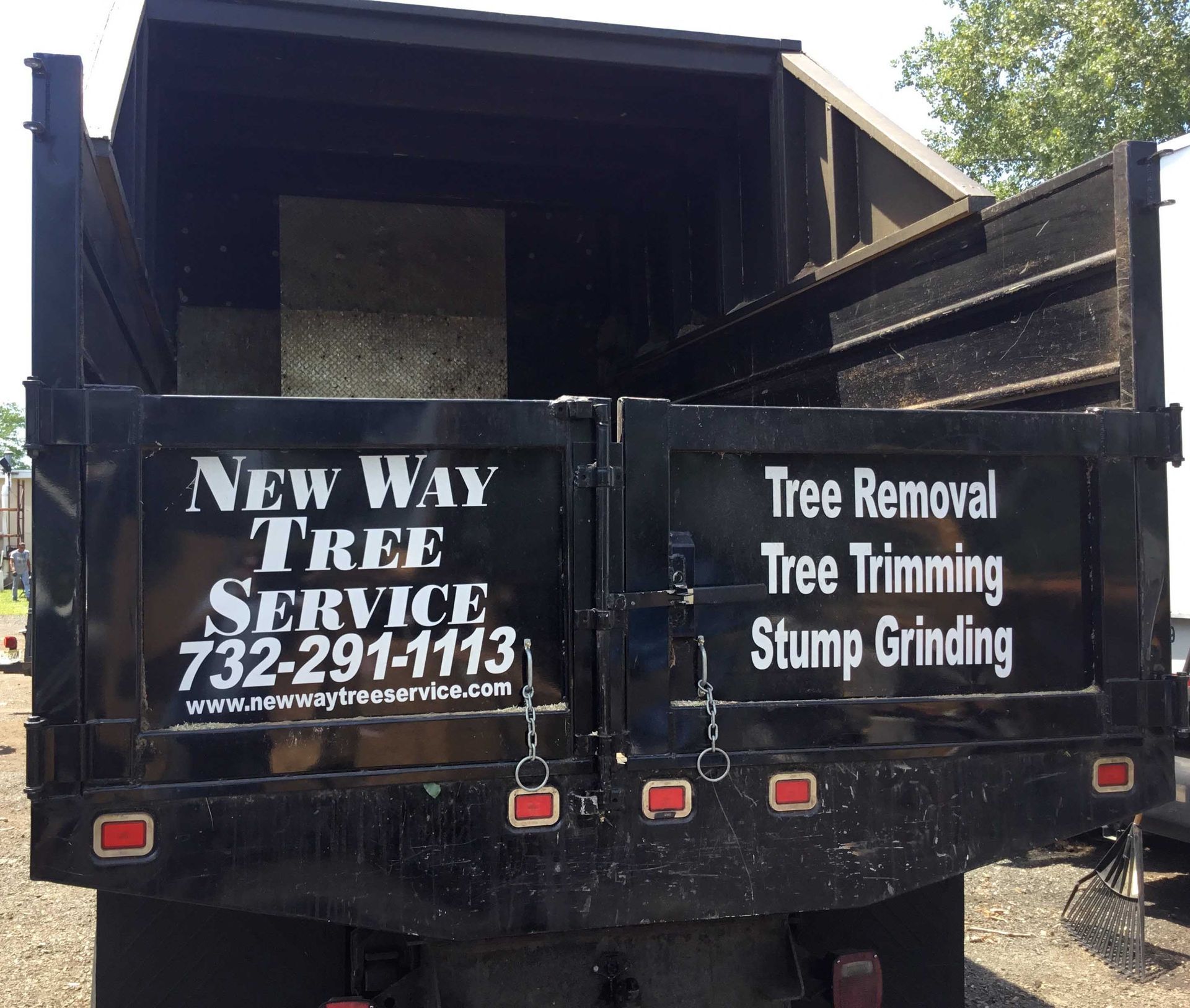 Black truck bed advertising New Way Tree Service, including tree removal, trimming, and stump grinding.