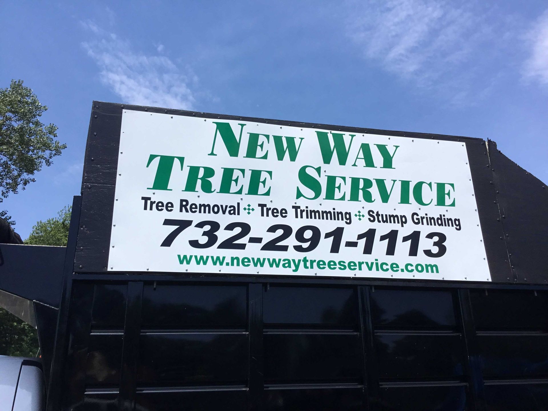 Sign for New Way Tree Service on a truck with contact information, featuring tree removal, trimming, and stump grinding services.