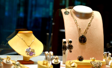 Jewelry display featuring two necklaces on stands, matching earrings, and assorted rings in a storefront showcase.