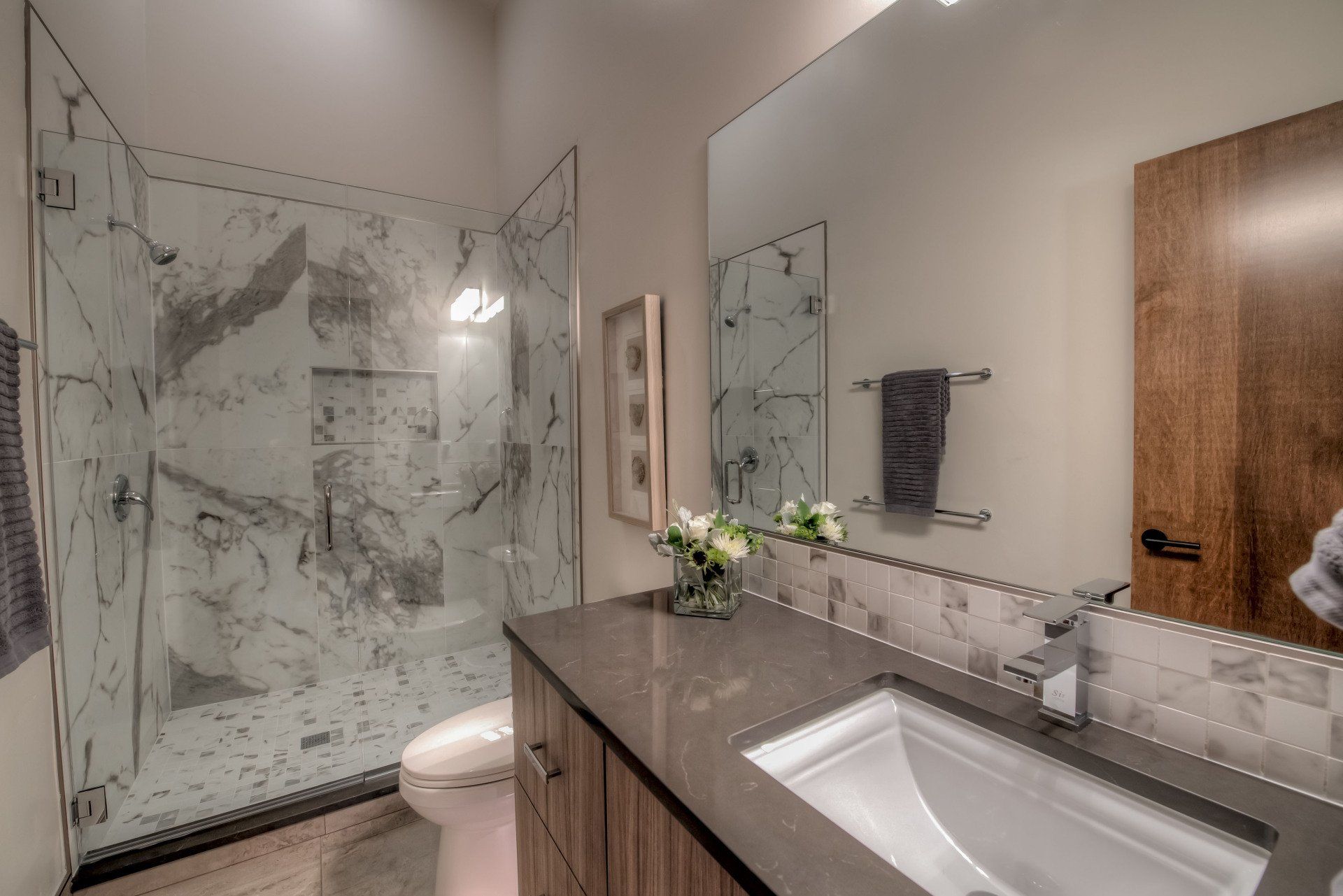 A bathroom with a sink , toilet , shower and mirror.