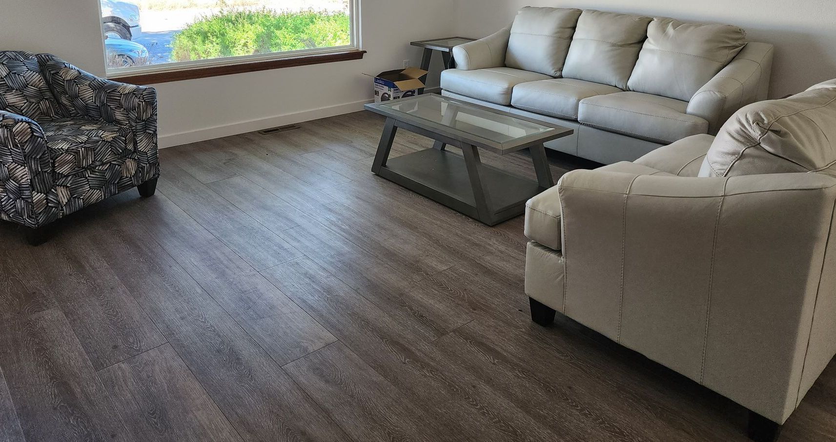 A living room with a couch , two chairs , a coffee table and a window.