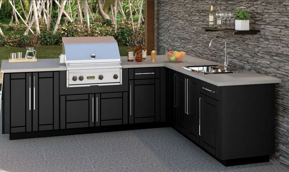 A kitchen with black cabinets , a grill and a sink.