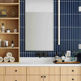 Modern bathroom with blue tile wall, wood cabinetry, and a large mirror above a white countertop
