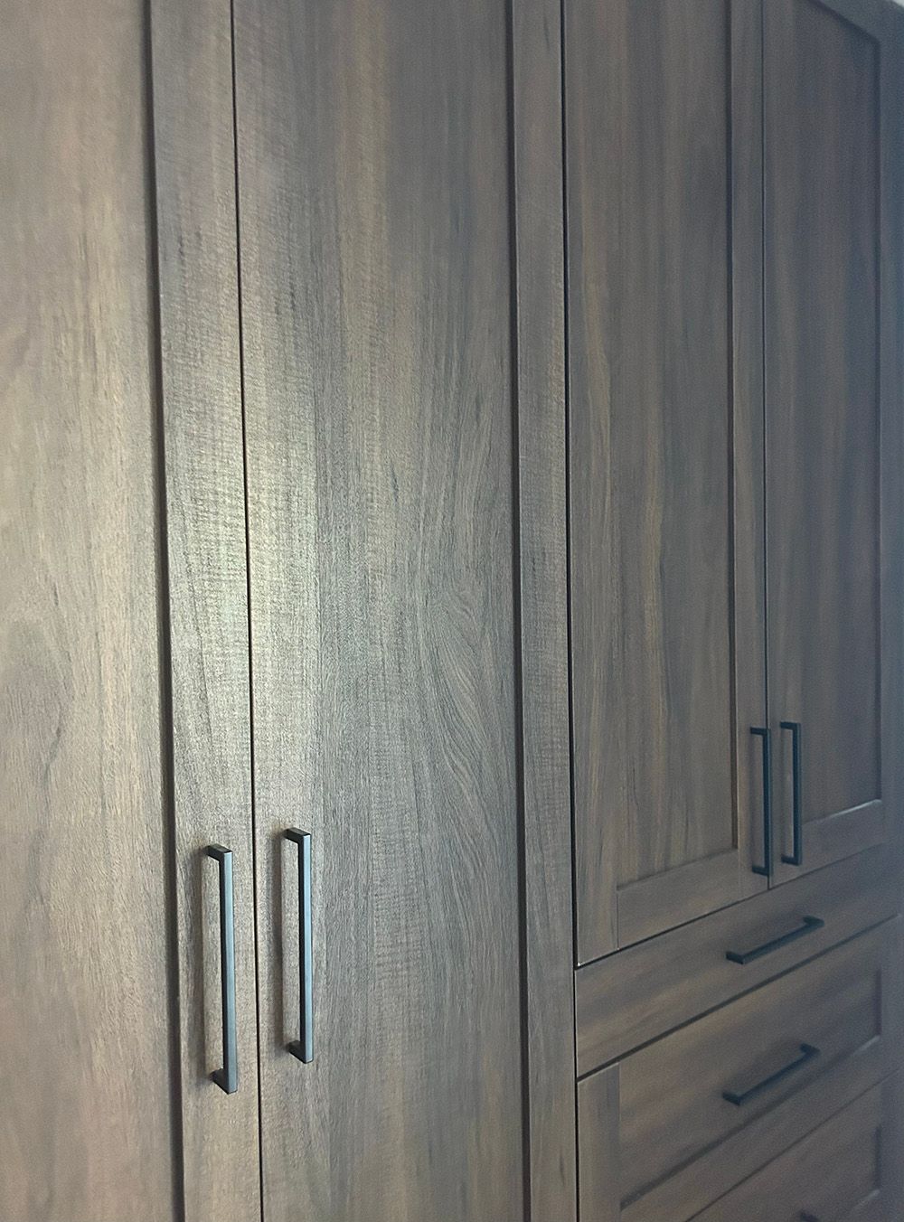 Wooden wardrobe with paneled doors and drawers in a bedroom or closet area.
