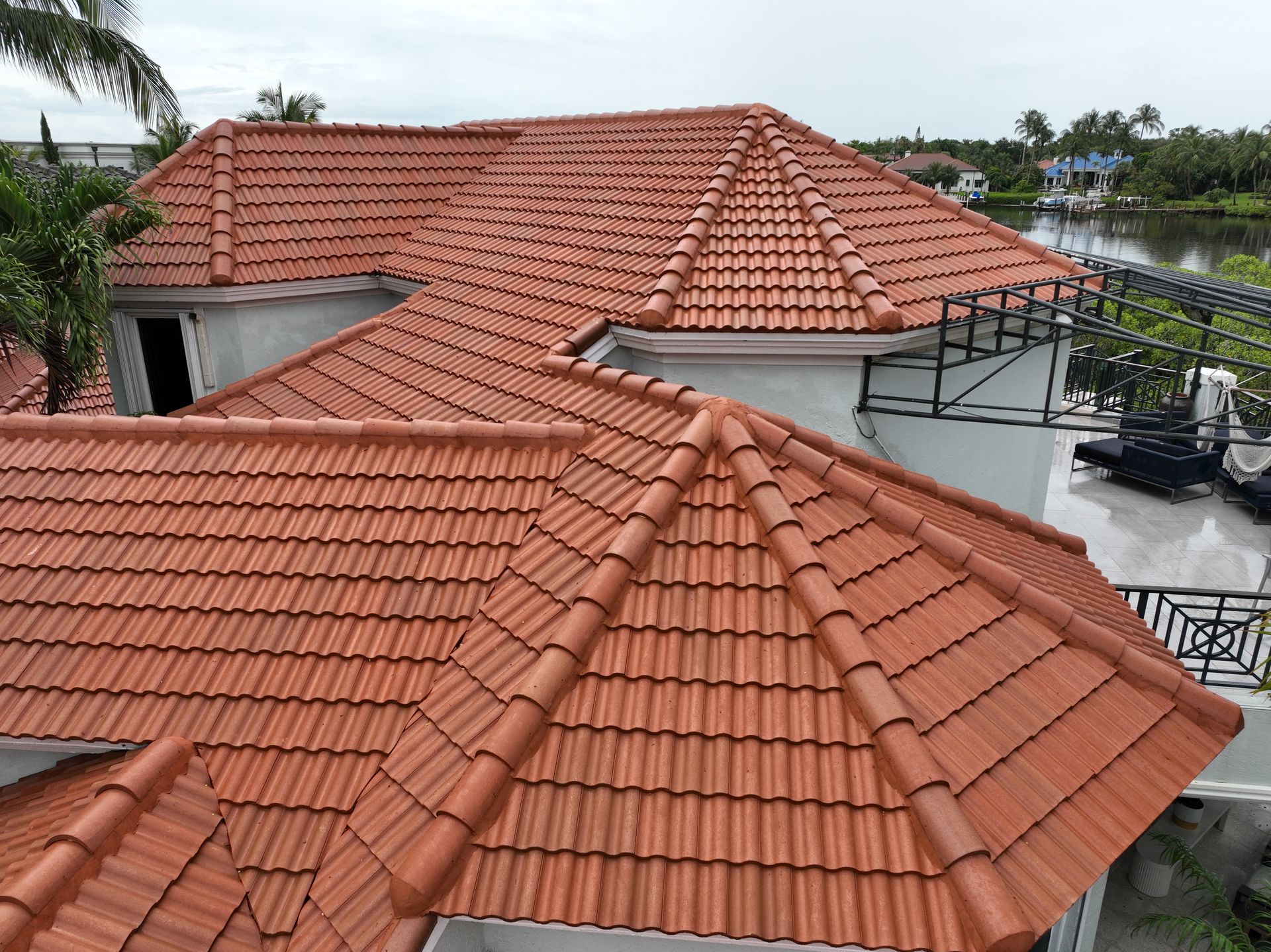 Red tile roof on a multi-gabled white house. The setting is tropical, near water.